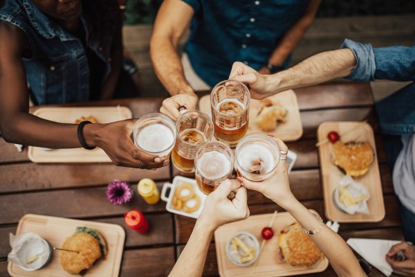 people-cheering-glasses-of-beer-and-eating-burgers