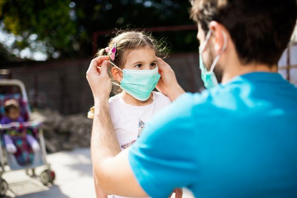 father-putting-face-mask-on-child