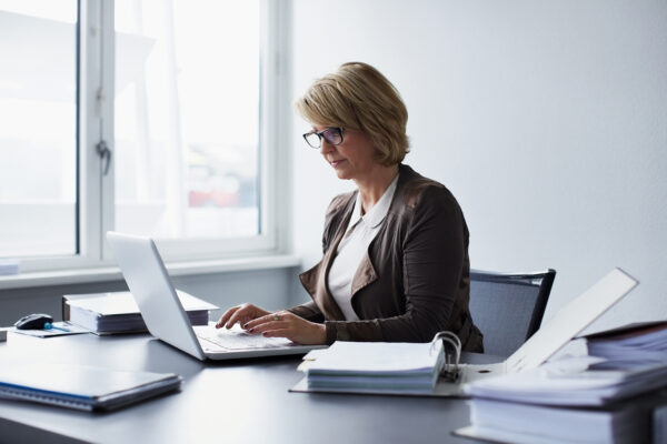 woman-at-work-on-computer-looking-over-files